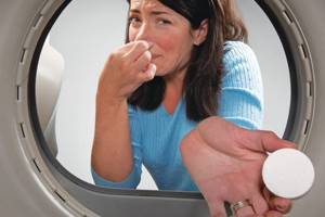 Женщина добавляет таблетку в барабан стиральной машины